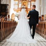 Photosession of stylish wedding couple on catholic church.